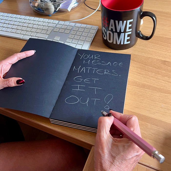 Notebook with the words ‘Your Message Matters. Get It Out!’ written in chalk, inspiring people to share their voice